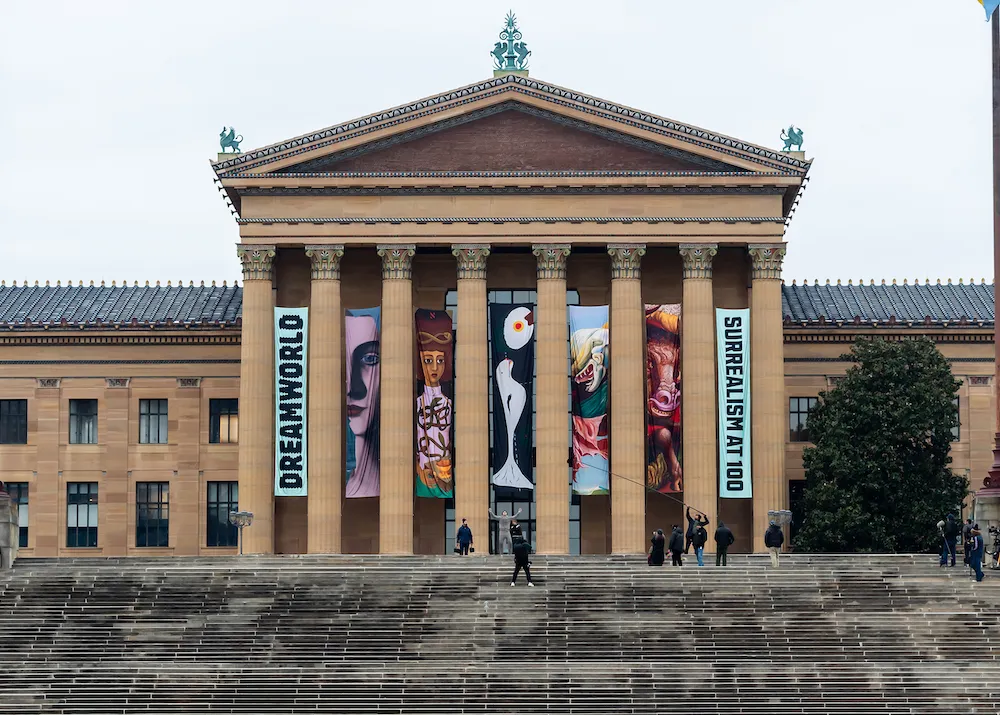 A museum facade with stairs leading down from it.