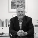 Portrait of Bob Monk seated at a desk with books behind him.