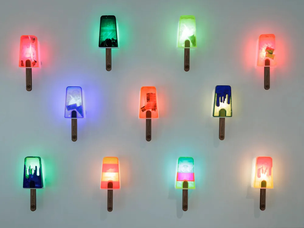 An installation of lit, brightly colored popsicle sticks.
