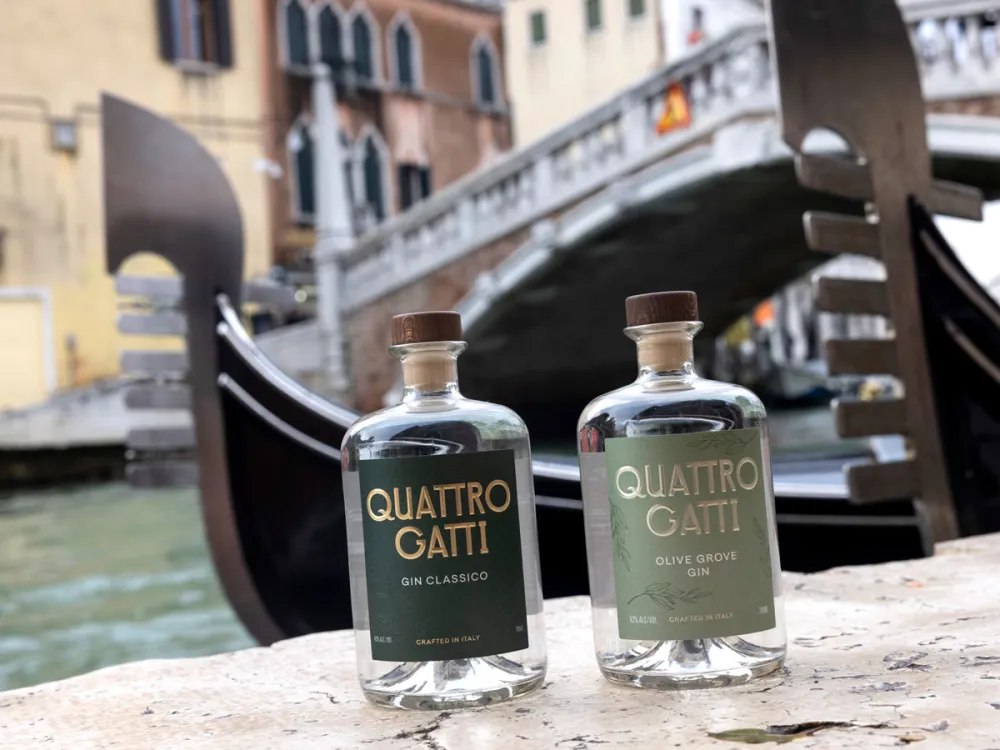 Two gin bottles on a brick wall near a canal in Venice, Italy.