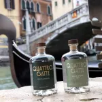Two gin bottles on a brick wall near a canal in Venice, Italy.