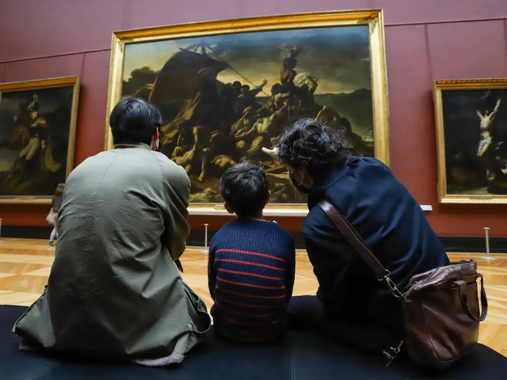 Three people on a bench looking at a large painting of people on a raft.