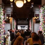 Crowds walk between flower covered columns at TEFAF New York.