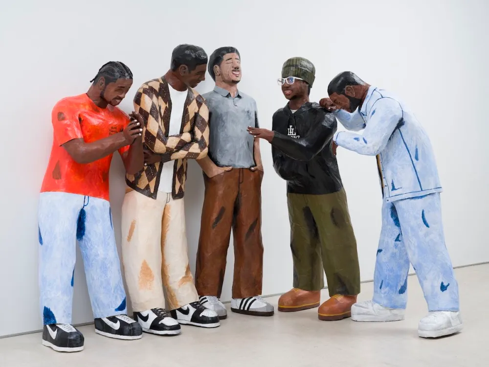 A group of sculptures of Black and Brown men smiling and laughing together.