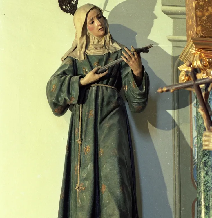 A photo shows a 5-foot wooden sculpture of a saint in antique robes, holding a cross.