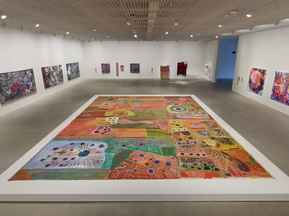 A gallery with paintings on its walls and a large painting on its floor.