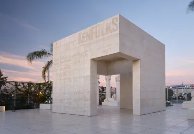 A concrete structure that has two large openings for doors. Etched into its surface are words such as 