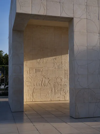 A concrete structure etched with various designs, including the silhouettes of heads.