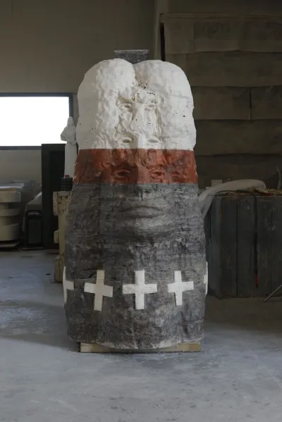 A totem like sculpture with two sets of eyes and a large mouth.