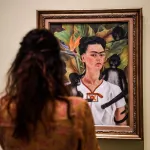 A person looking at a painting of a woman surrounded by monkeys.