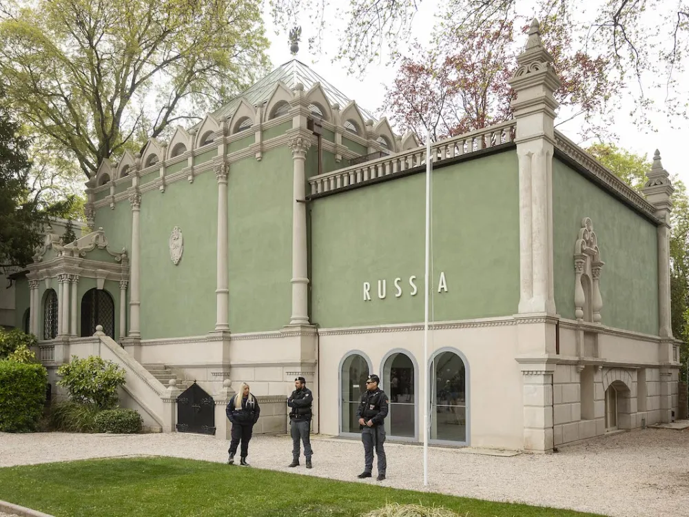 Three guards standing before a blocky green pavilion that has the word 