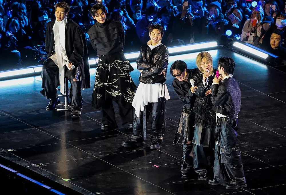 four young korean men on stage with microphones