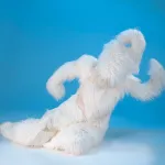 A humanoid figure, covered in soft looking white hair, makes muscles.