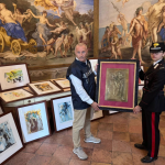 A man and woman hold a painting.