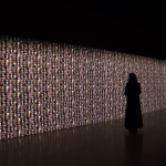 A woman staring at a glowing wall.