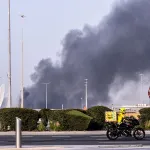 A food delivery bike drive close to a plume of smoke rising from the Zayed Port following a reported Iranian strike in Abu Dhabi on March 1, 2026. Iran