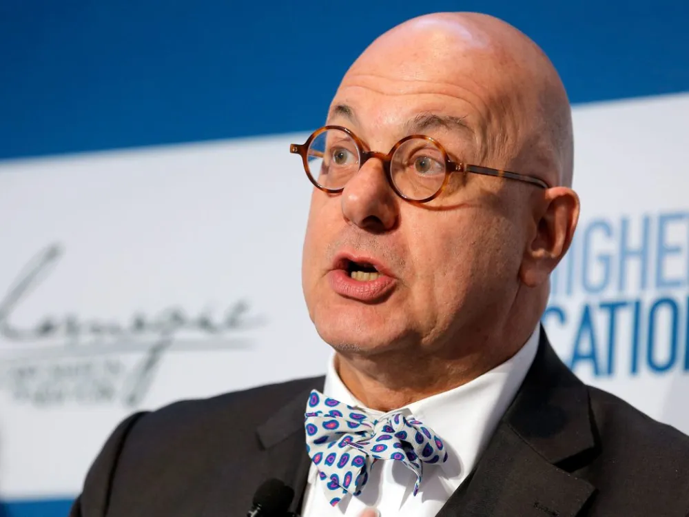 A man with a bald head, round glasses, and a bowtie.