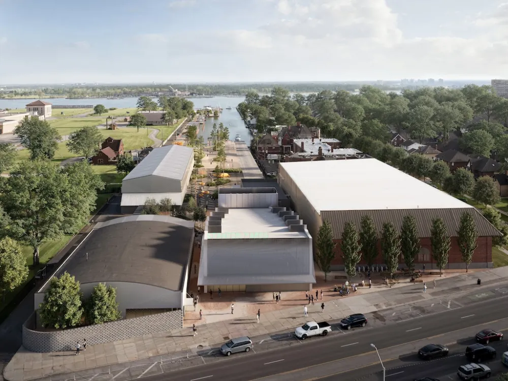 A Ariel view of warehouse building surrounded by trees with a like or river in the background.