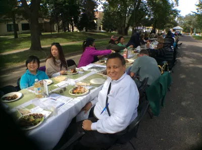 People sit at a long table eating a meeting at a community party. 