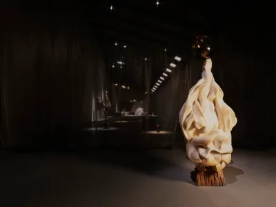 A darkened gallery with a white, flowy sculpture.