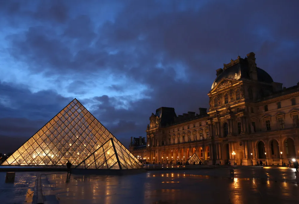 A glass pyramid structure next to a classical building.