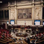 A large assembly room with grand sculptures and a painting in the center.