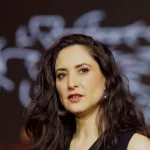 A woman with long brown hair in a close-up profile.