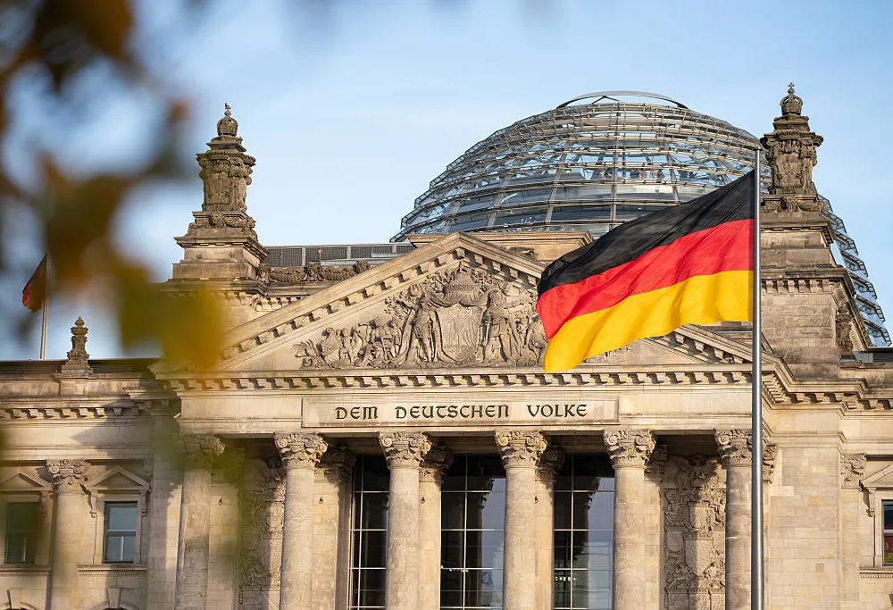 A German flag flying in front of a columned building.