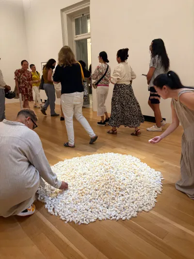 People pick-up candy from a Felix Gonzalez-Torres pile in a museum.