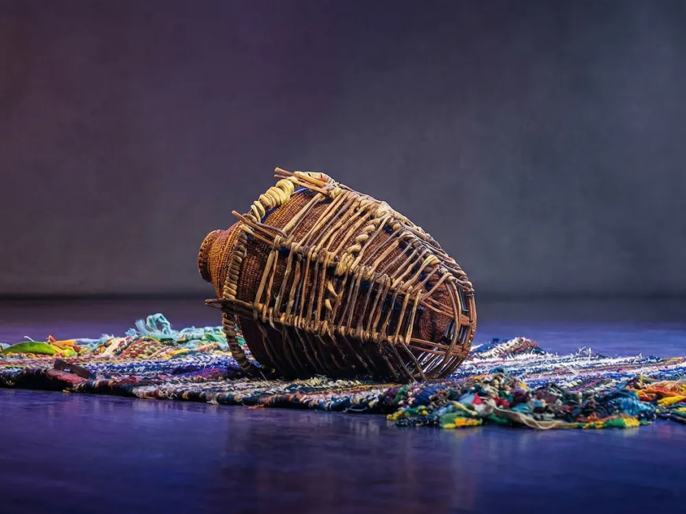 A basket-like structure resting atop a rug.