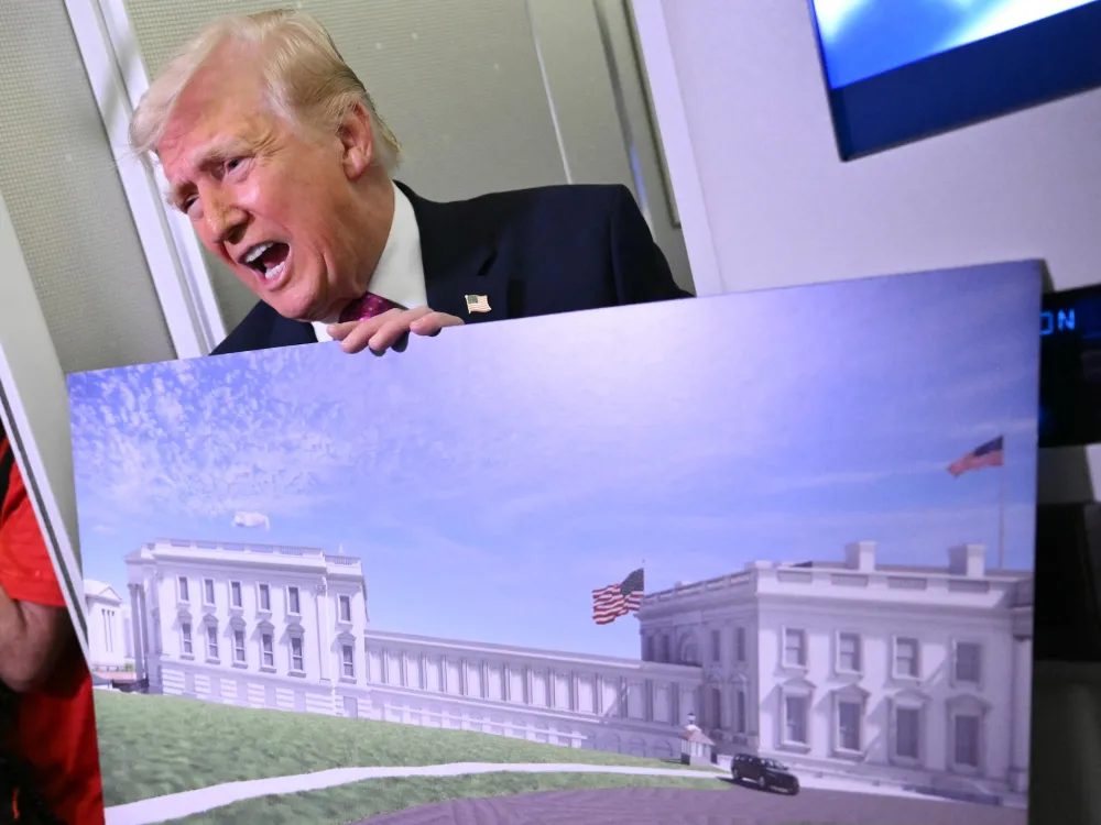 US President Donald Trump holds a rendering of the East Wing modernization as he speaks to reporters aboard Air Force One