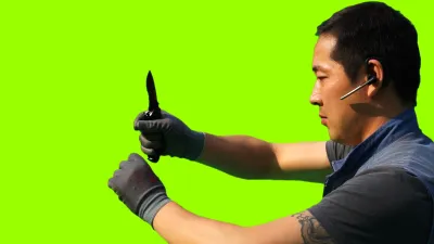 A man holding a knife in front of a bright green background.