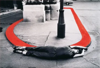 A woman lies around a curb, which is painted red. 