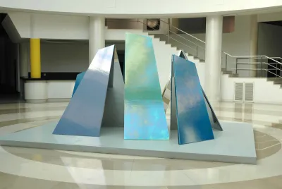 A group of reflective monolith-like structures leaned together in an atrium.
