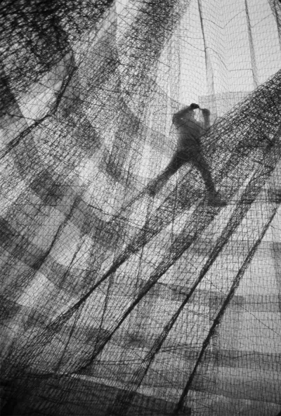 A man in a large structure made of netted wire.