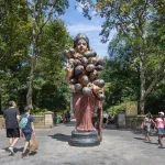 A large sculpture of a woman with multiple heads sprouting from her torso stands in a clearing in Central Park.