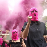 Pussy Riot and FEMEN protest outside the Russian pavilion at the Venice Biennale, wearing pink balaclavas and sending forth pink smoke.
