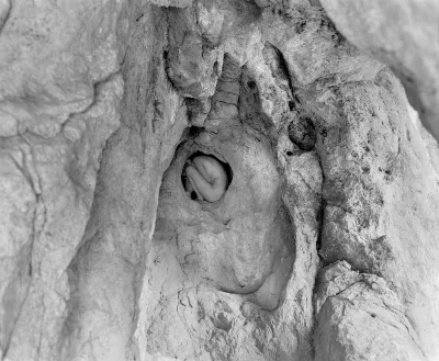 A person curled up in a hole in a canyon.