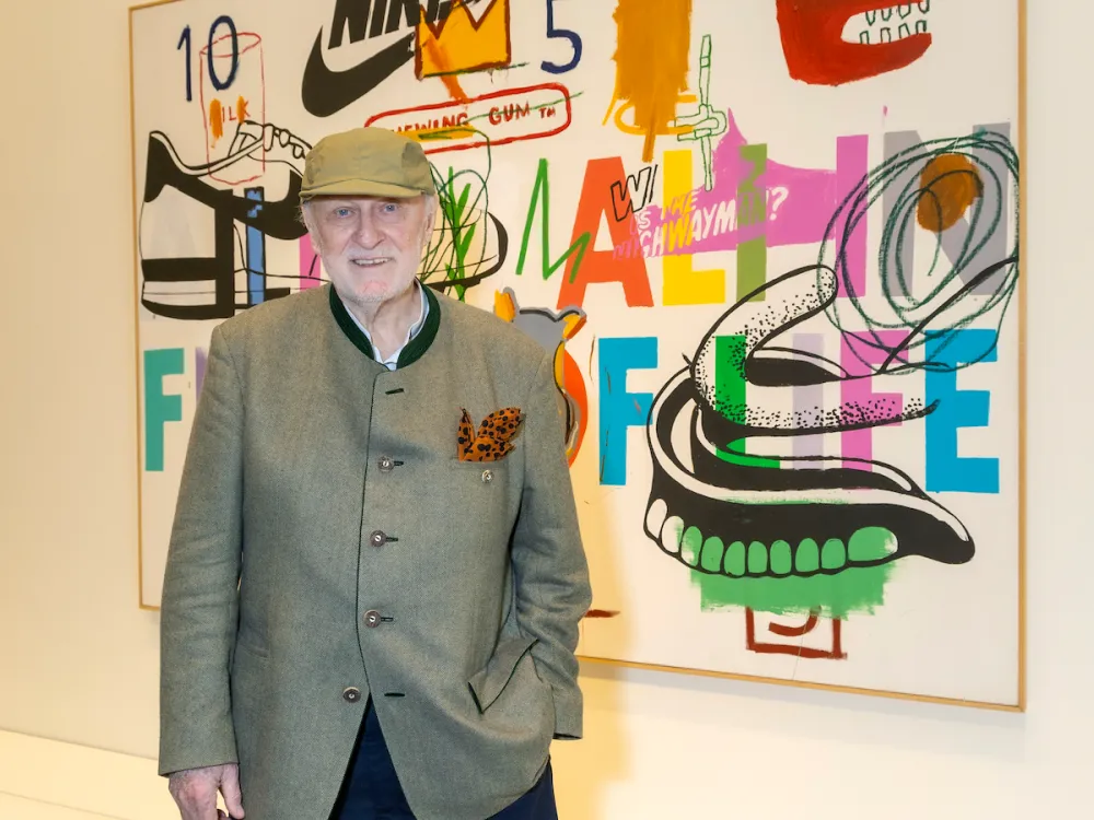 A man in a suit jacket standing in front of an abstract painting.