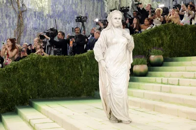 A woman dressed as a white sculpture on a staircase.