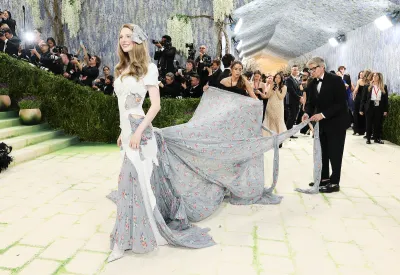 A woman wearing a long dress printed with flowers, along with a white element that partially covers it that appears to have been torn away in parts.