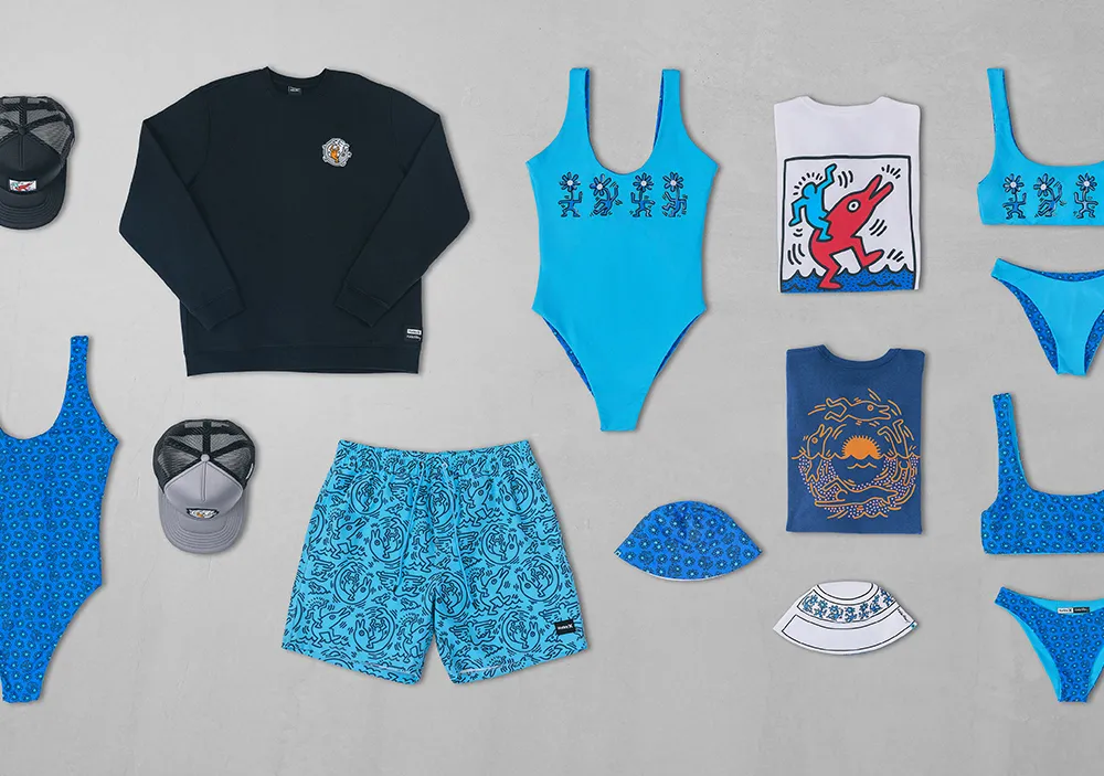 vairous clothing items, like bathing suits, hats, and t-shirts, in shades of blue and covered with graphic drawings in a graffiti-style