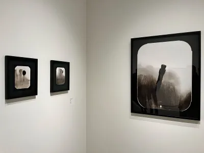 Three photographs hang on two walls.
