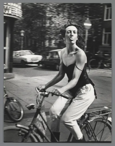 A woman on a bicycle sticking her tongue out.