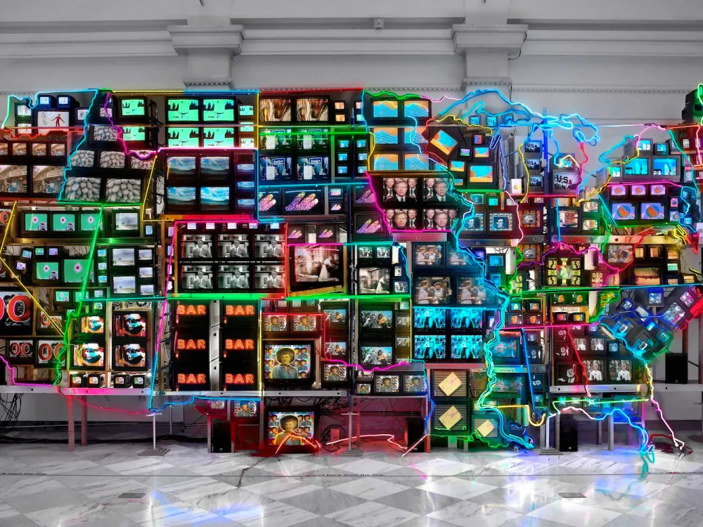 An installation resembling a map of the United States with neon delineating the border of each state. Each state contains multiple video monitors.