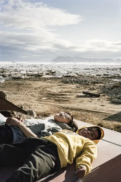 Two people lying on a raised surface in front of a field of ice.