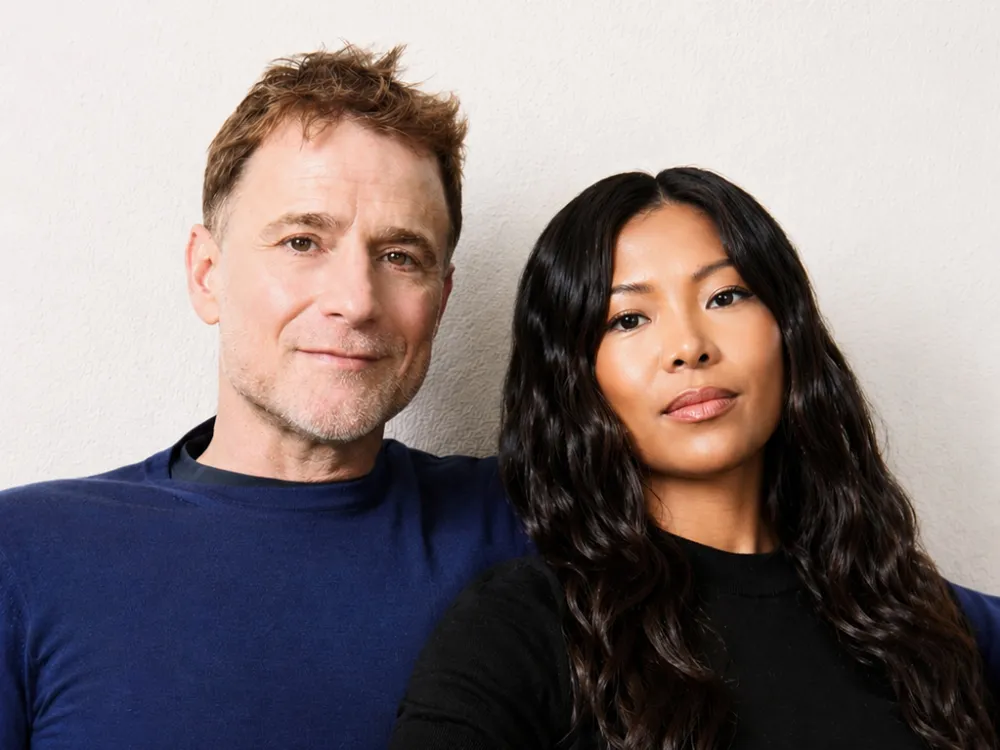 a man with short hair and a blue shirt next to a woman with long dark hair and a black shirt