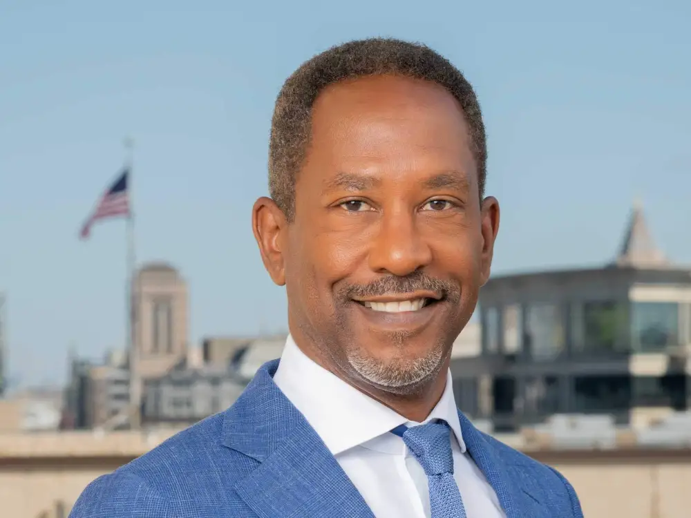 A man in a suit with an American flag in the background.