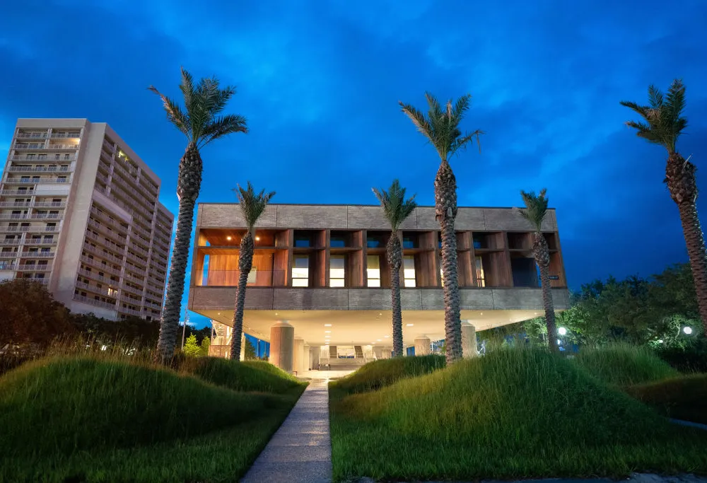 The tired museum facade flanked by palm trees and set against a deep blue sky.