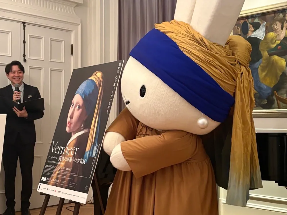 An oversized doll wearing a blue and gold turban and one giant pearl earring.